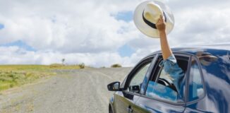 pasażer machający kapeluszem przez uchylone okno w samochodzie