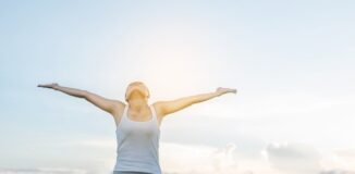 Kobieta z rozłożonymi ramionami wdycha świeże powietrze